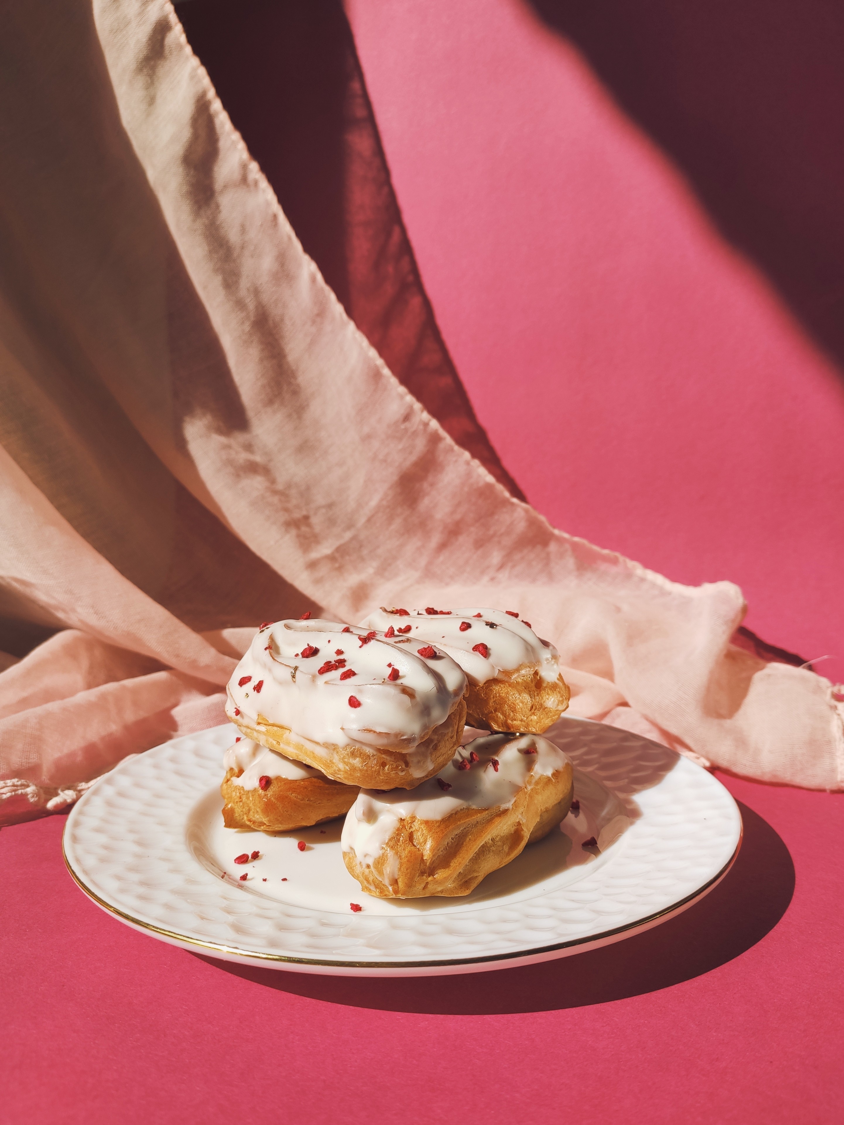 Delicious eclairs on a plate decorated with dried raspberries