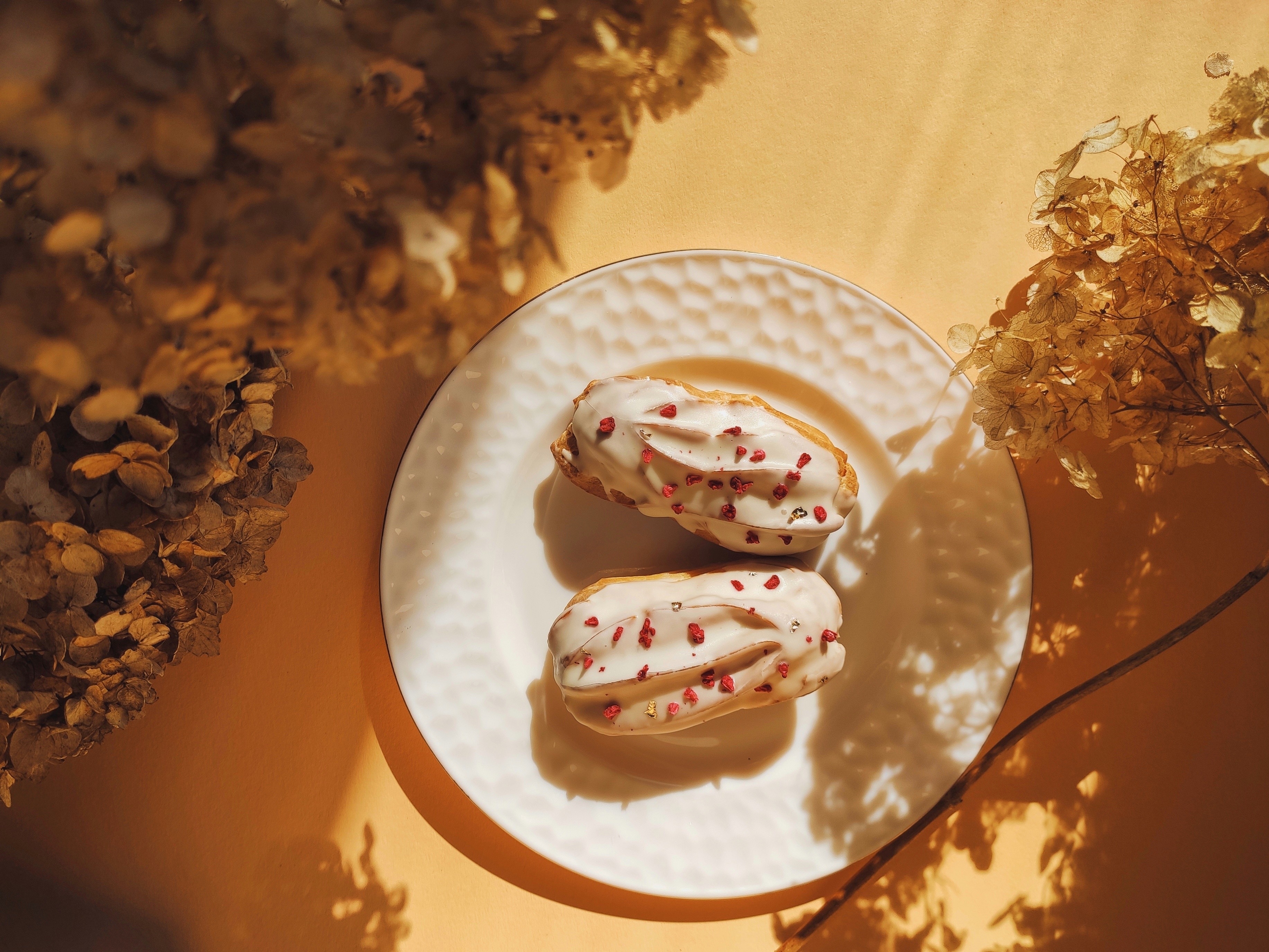 Exquisitos eclairs con glaseado blanco y migas de frambuesa