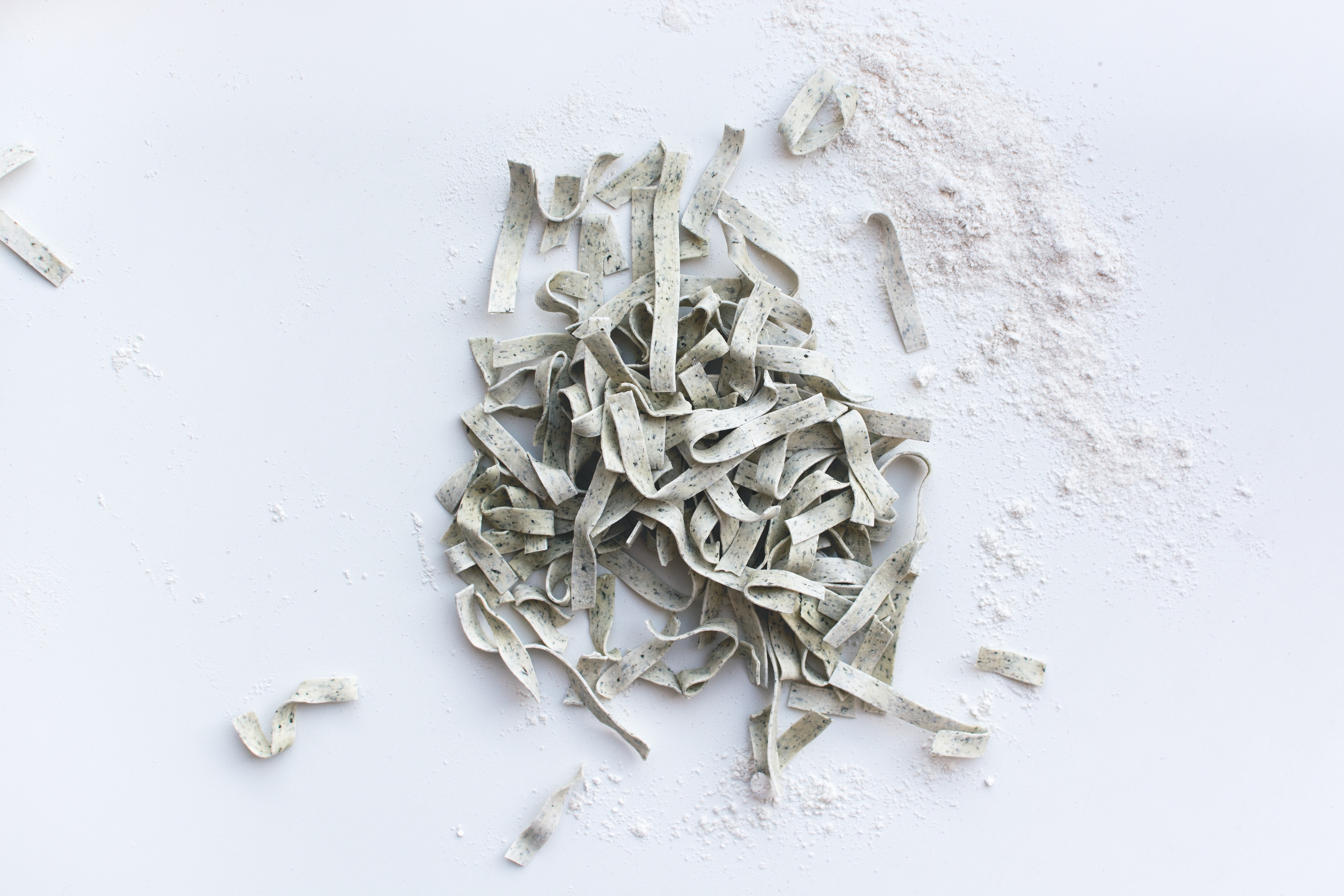 Tagliatelle coberto de farinha em um fundo branco