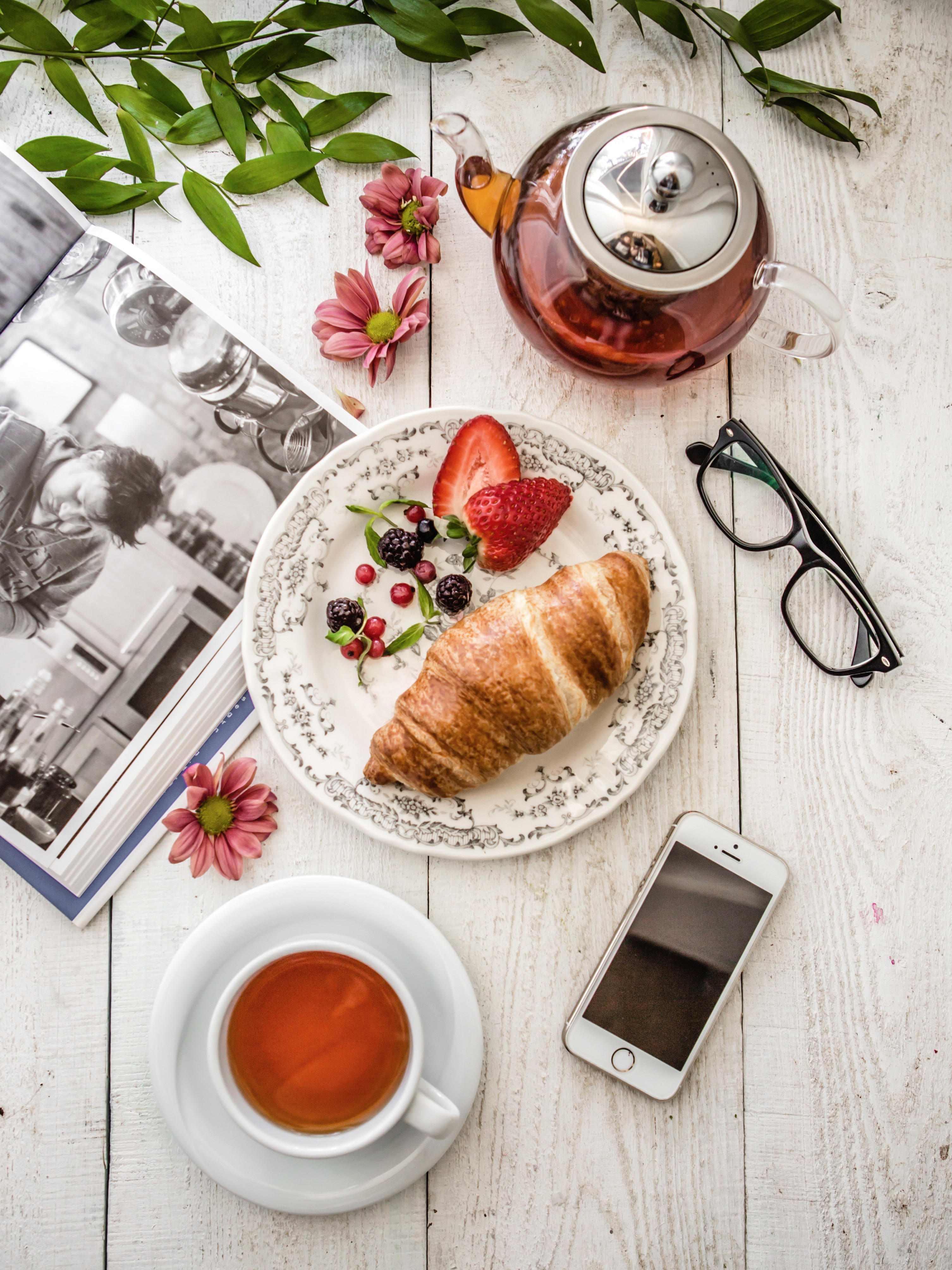 Relaxando com livro, chá, croissant e frutas vermelhas