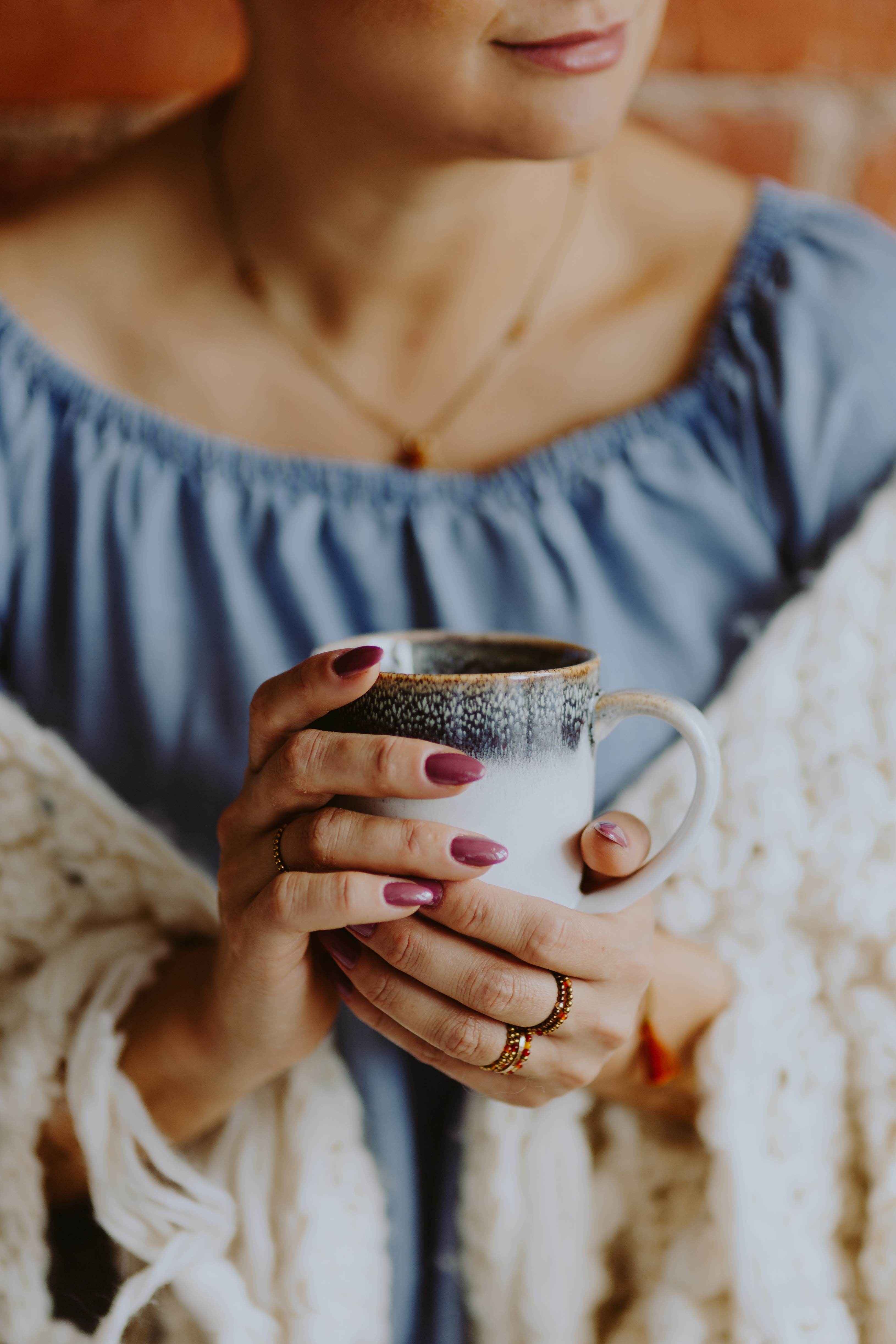 Mulher em um cobertor quente segurando uma xícara de café