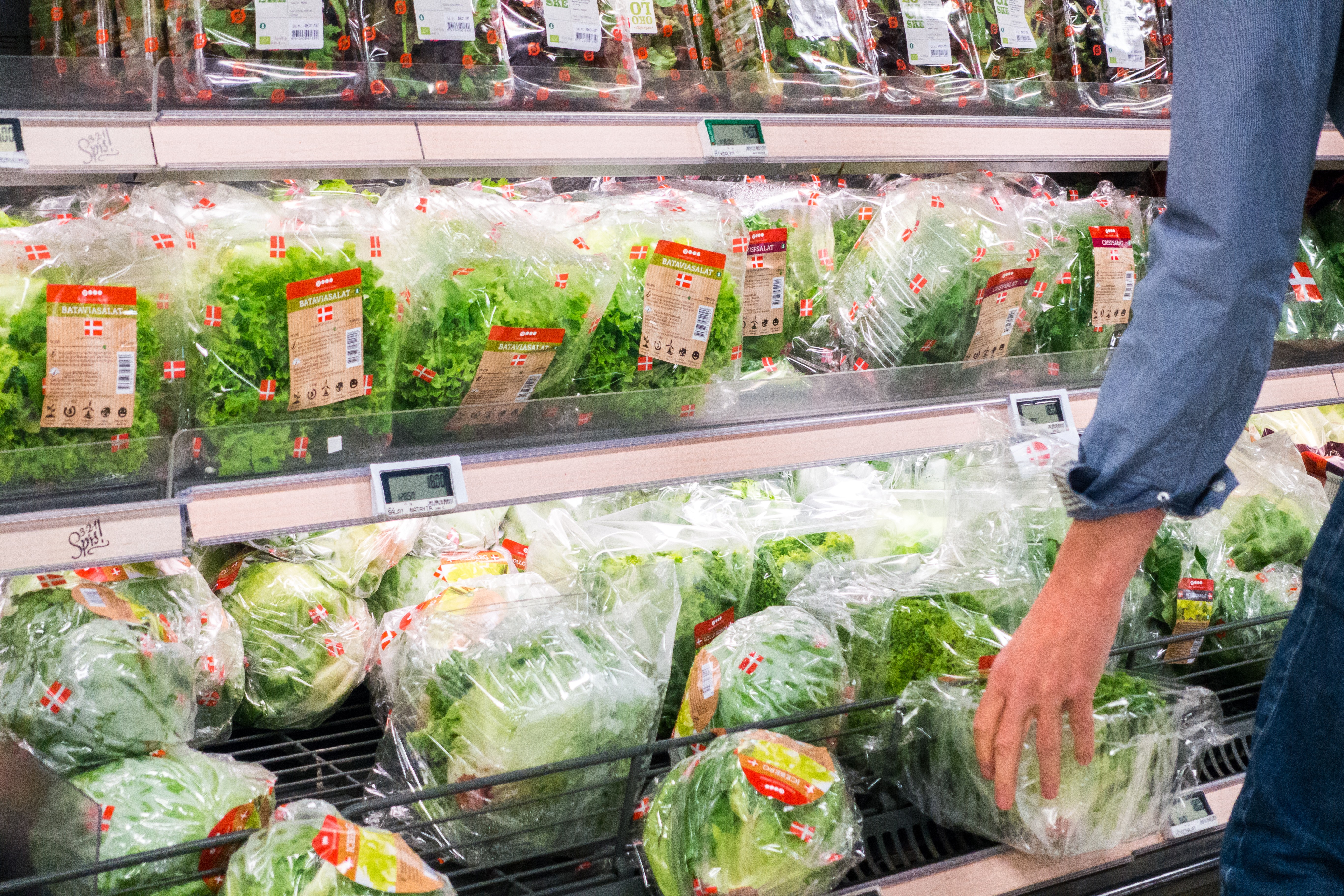 Женщина выбирает салат в продуктовом магазине